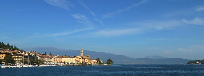 Pauschal beliebte Urlaubsziele am Gardasee -  Mit einer Fläche von 370 km² ist der Gardasee der größte See Italiens. Es liegt am Fuße der Alpen und erstreckt sich über drei Staaten: Lombardei, Venetien und Trentino. Die maximale Tiefe des Sees beträgt 346 m, er hat eine längliche Form und sein nördliches Ende ist sehr schmal. Dort ist der See von den Bergen der Gruppo di Baldo umgeben. Du trittst aus deinem gemütlichen Hotelzimmer und es begrüßt dich die warme italienische Sonne. Du blickst auf den atemberaubenden Gardasee, der in zahlreichen Blautönen schimmert - von tiefem Dunkelblau bis zu funkelndem Türkis. Majestätische Berge umgeben dich, während die Brise sanft deine Haut streichelt und der Duft von blühenden Zitronenbäumen deine Nase kitzelt. Du schlenderst die malerischen, engen Gassen entlang, vorbei an farbenfrohen, blumengeschmückten Häusern. Vereinzelt unterbricht das fröhliche Lachen der Einheimischen die friedvolle Stille. Du fühlst dich wie in einem Traum, der nicht enden will. Jeder Schritt führt dich zu neuen Entdeckungen und Abenteuern. Du probierst die köstliche italienische Küche mit ihren frischen Zutaten und verführerischen Aromen. Die Sonne geht langsam unter und taucht den Himmel in ein leuchtendes Orange-rot - ein spektakulärer Anblick.